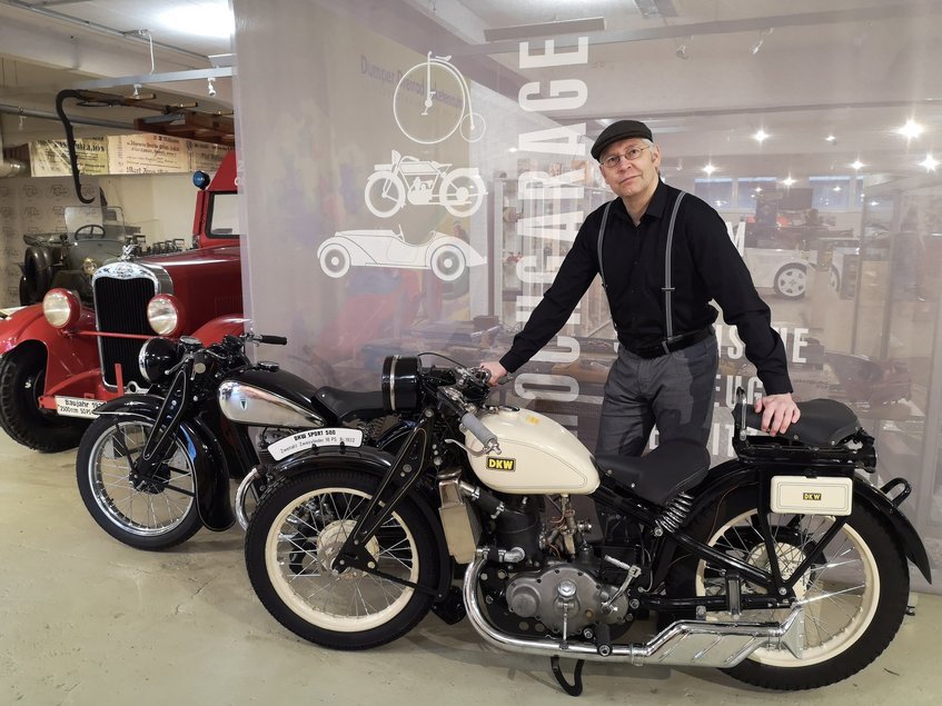 Auf dem Foto steht Museumsleiter Dirk Schmerschneider vor zwei Exponaten der Sonderausstellung „Vom Arschwärmer zum Stachelschwein – 100 Jahre DKW-Motorradbau“: einer DKW Sport 500 von 1932 und einer DKW SB 200 von 1937.