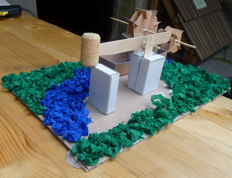 Das Foto zeigt ein ein kleines funktionstüchtiges Hammerwerk, das sich die Kinder im Anschluss an diese Führung selbst aus Papier basteln können.