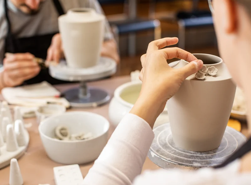 Im Kreativ-Workshop verziert eine Teilnehmerin einen Porzellanbecher mit kleinen Blüten – konzentriert und handwerklich.