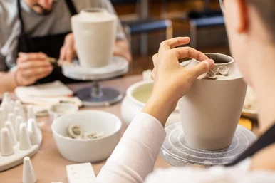Im Kreativ-Workshop verziert eine Teilnehmerin einen Porzellanbecher mit kleinen Blüten – konzentriert und handwerklich.