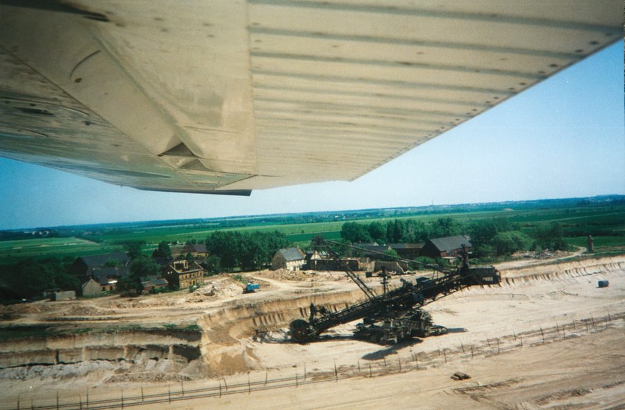 Das Bild zeigt einen Tagebau und Häuser, welche vor der Zerstörung stehen