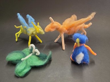 Vier kleine, aus verschiedenfarbiger Wolle kreierte Tierfiguren