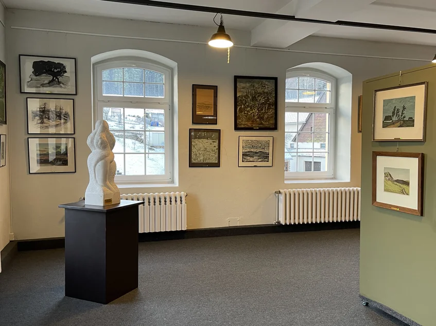 Kunstblicke auf das Erzgebirge Ausstellungsraum mit Landschaftsbildern zwischen großen Rundbogenfenstern; auf einem Sockel steht eine Skulptur.