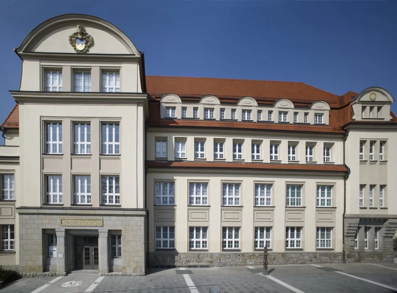 Großes, vierstöckiges Gründerzeitgebäude. Linksseitig herausstehend der Portal und Treppenhaus beherbergende Gebäudeteil.