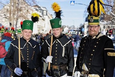 Drei in traditionelle Schmuck-Uniformen gekleidete erzgebirgische Bergmänner vor einer größeren Besuchermenge