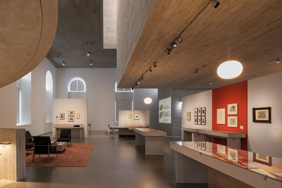 Ausstellungsraum mit präsentierten Bildern an den Wänden und in Vitrinen