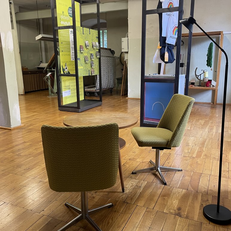Ausstellungsraum mit textil-gepolsterten Drehsesseln und im Hintergrund Ausstellungs-Schauwänden