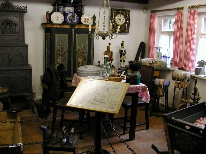 Heimatstube Museale Inszenierung einer historischen Wohnstube mit bemaltem Wandschrank, verziertem Kachelofen und mehreren Klöppelsäcken