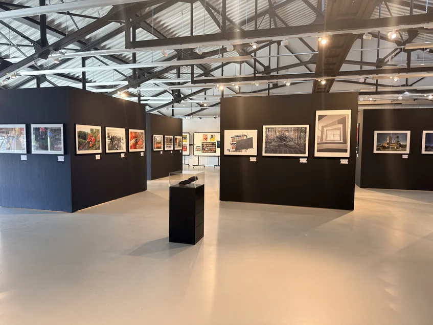 Blick in die Sonderausstellung „Kohlenstaub auf Polaroid. 40 Jahre Museum im Schacht“ Großer Raum mit schwarzen Ausstellungswänden, an denen großformatige Fotografien präsentiert werden