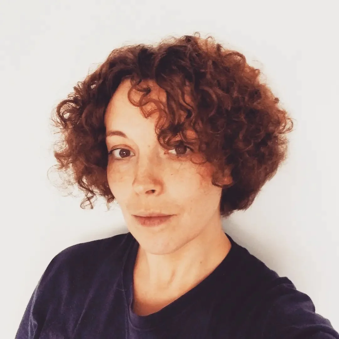 Katerina Kuznetsova Porträtfoto von Katerina Kuznetsova, einer Frau mit lockigen dunklen Haaren, die hier den Betrachtenden direkt anblickt