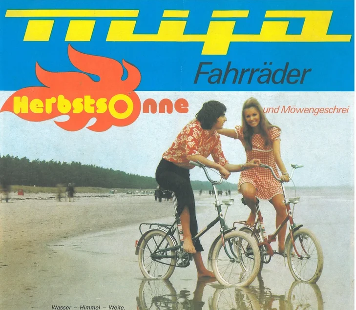 Werbemotiv aus den 1970er Jahren: Ein Mann und eine Frau auf Klappfahrrädern der DDR-Marke Mifa am Ostsee-Strand