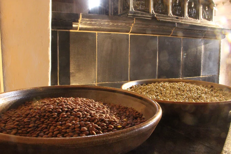 Eine Schüssel Linsen und eine Schüssel Erbsen stehen auf einer Ablage vor einem historischen Kachelofen.