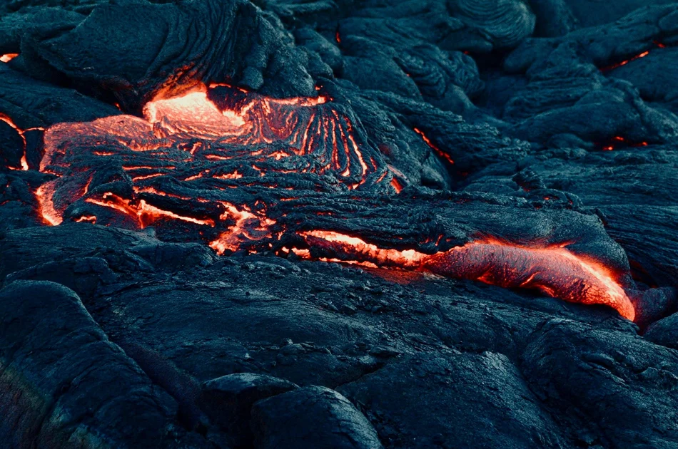 Lava oder Magma? Leuchtende, glühende Lava bahnt sich den Weg durch dunkles Gestein.