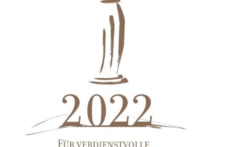 Das Foto zeigt das Logo der Auszeichnung für verdienstvolle ehrenamtliche Arbeit zur Förderung der sächsischen Kultur 2022. Es enthält eine von einem kleinen, geschwungenen „e“ gekrönte, stilisierte klassizistische Säule.