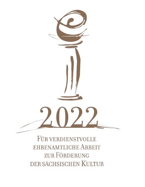Das Foto zeigt das Logo der Auszeichnung für verdienstvolle ehrenamtliche Arbeit zur Förderung der sächsischen Kultur 2022. Es enthält eine von einem kleinen, geschwungenen „e“ gekrönte, stilisierte klassizistische Säule.