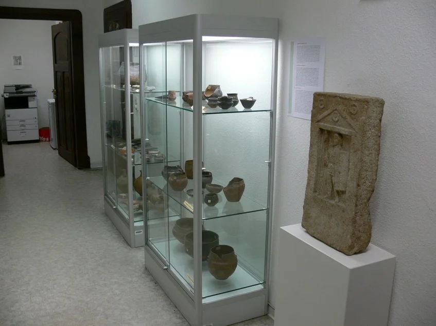 Flur: Vitrinen mit Grabkeramik der Bronze- und Eisenzeit, Grabstein eines römischen Soldaten