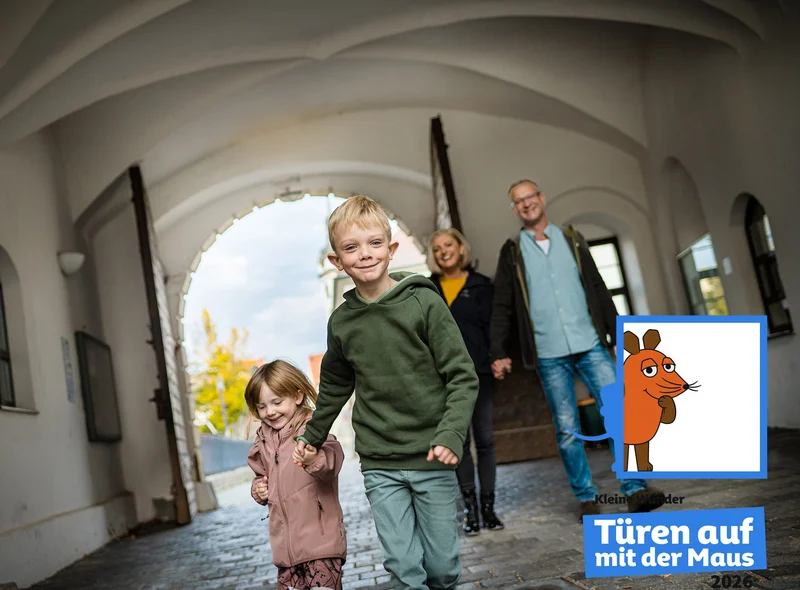 Ein Junge (ca. 7) und ein Mädchen (ca. 5 Jahre) rennen lachend durch den Torbogen in den Innenhof von Schloss Hartenfels.