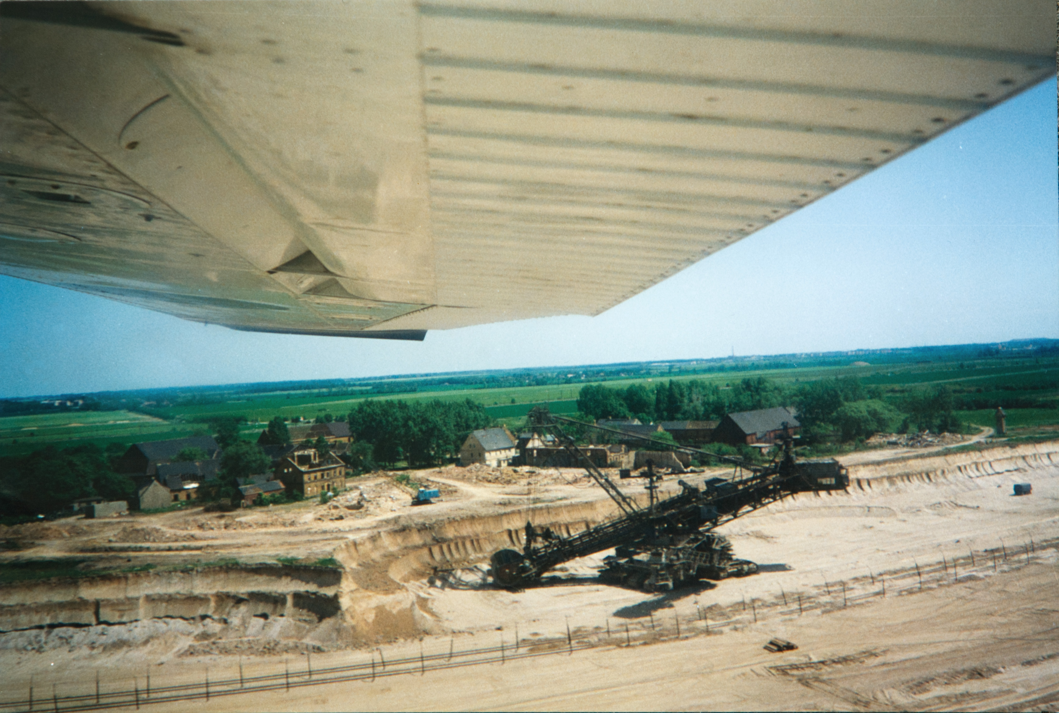Das Bild zeigt einen Tagebau und vor der Zerstörung stehende Häuser