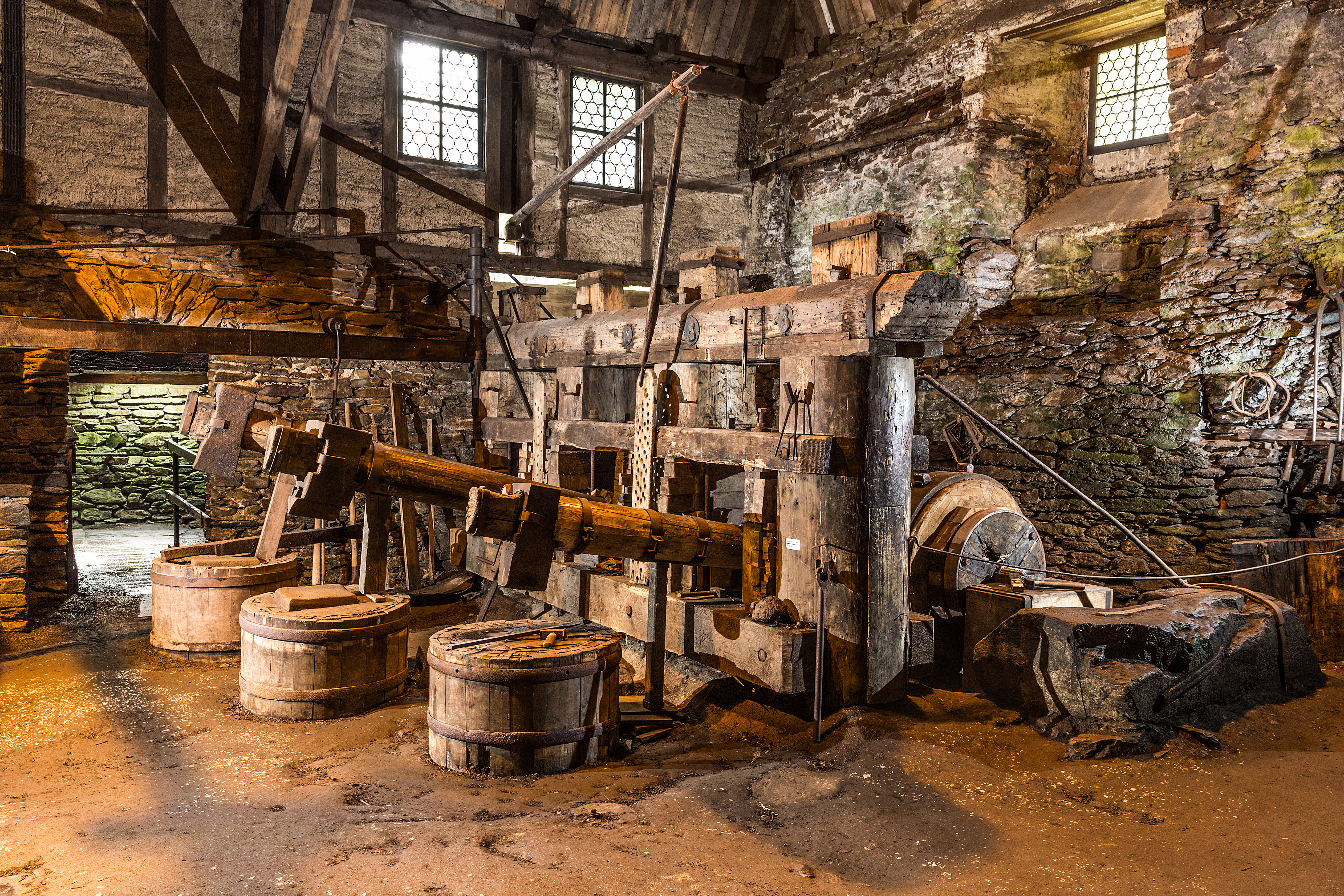Historische Schmiede mit riesigen Hämmern in einem alten Gebäude mit Natursteinmauern
