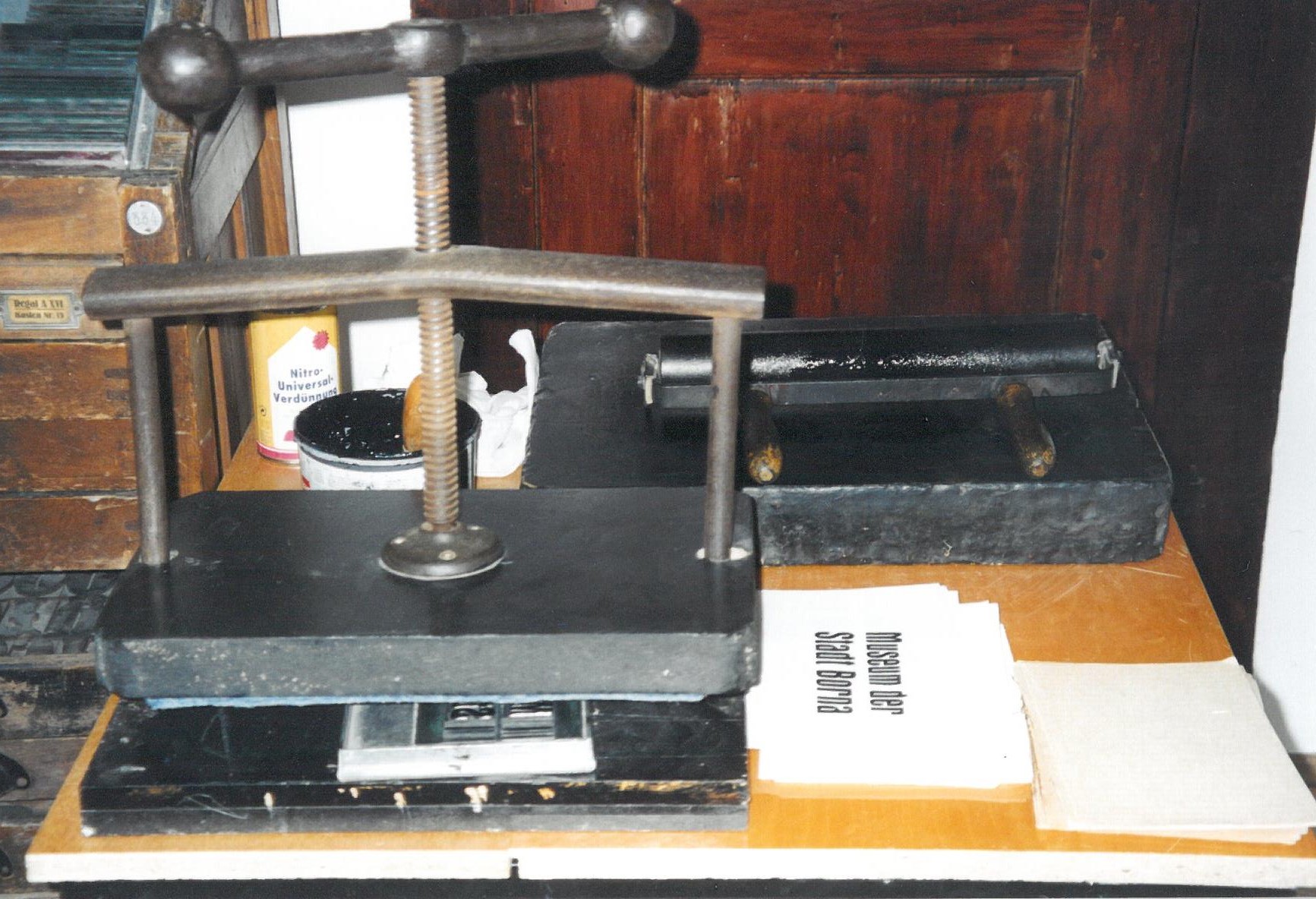 Das Foto zeigt eine alte Druckpresse und ein bedrucktes Papier.