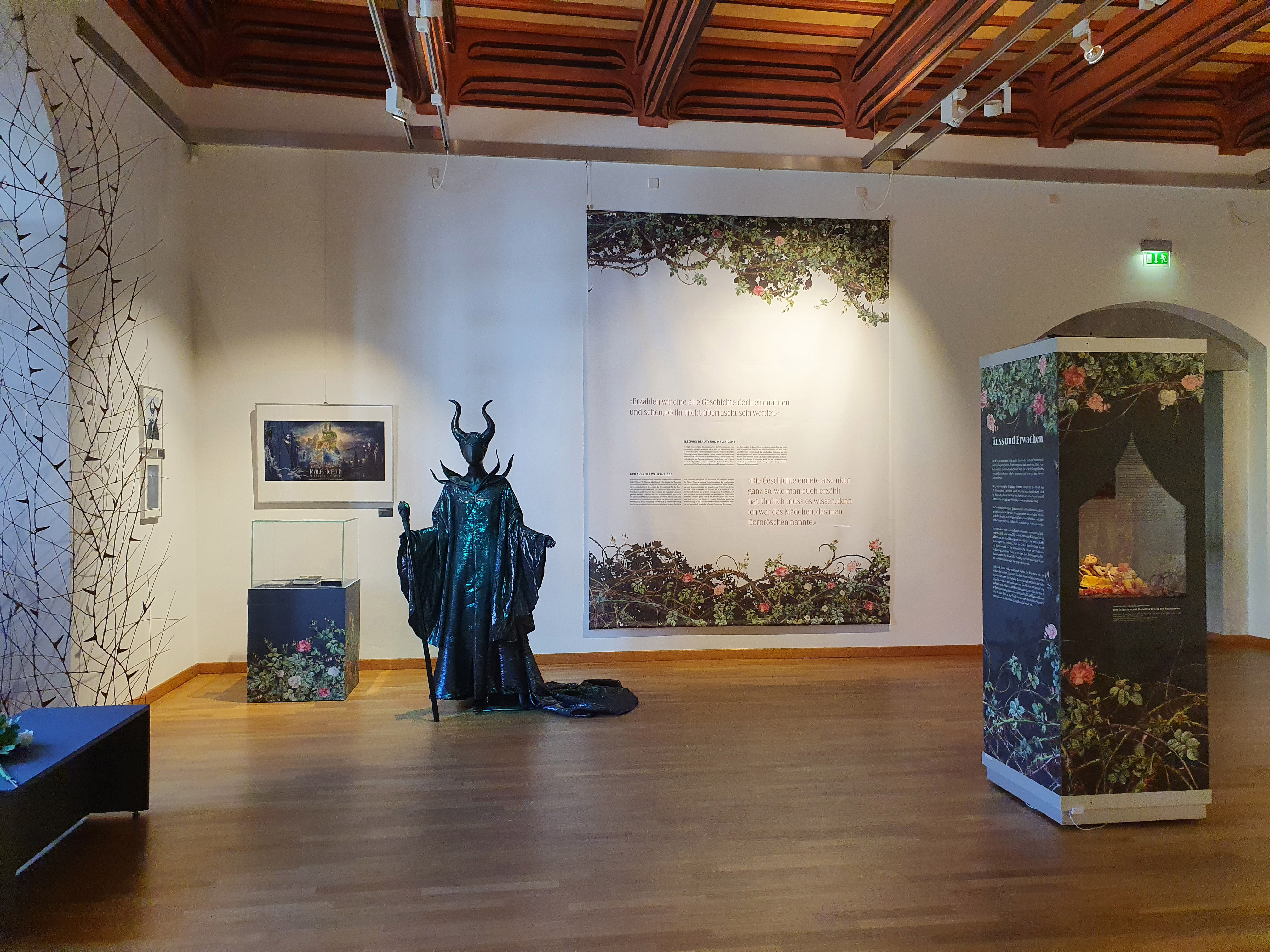 Foto eines Ausstellungsraums mit Wandtexten und der lebensgroßen Figur der bedrohlich wirkenden bösen Königin