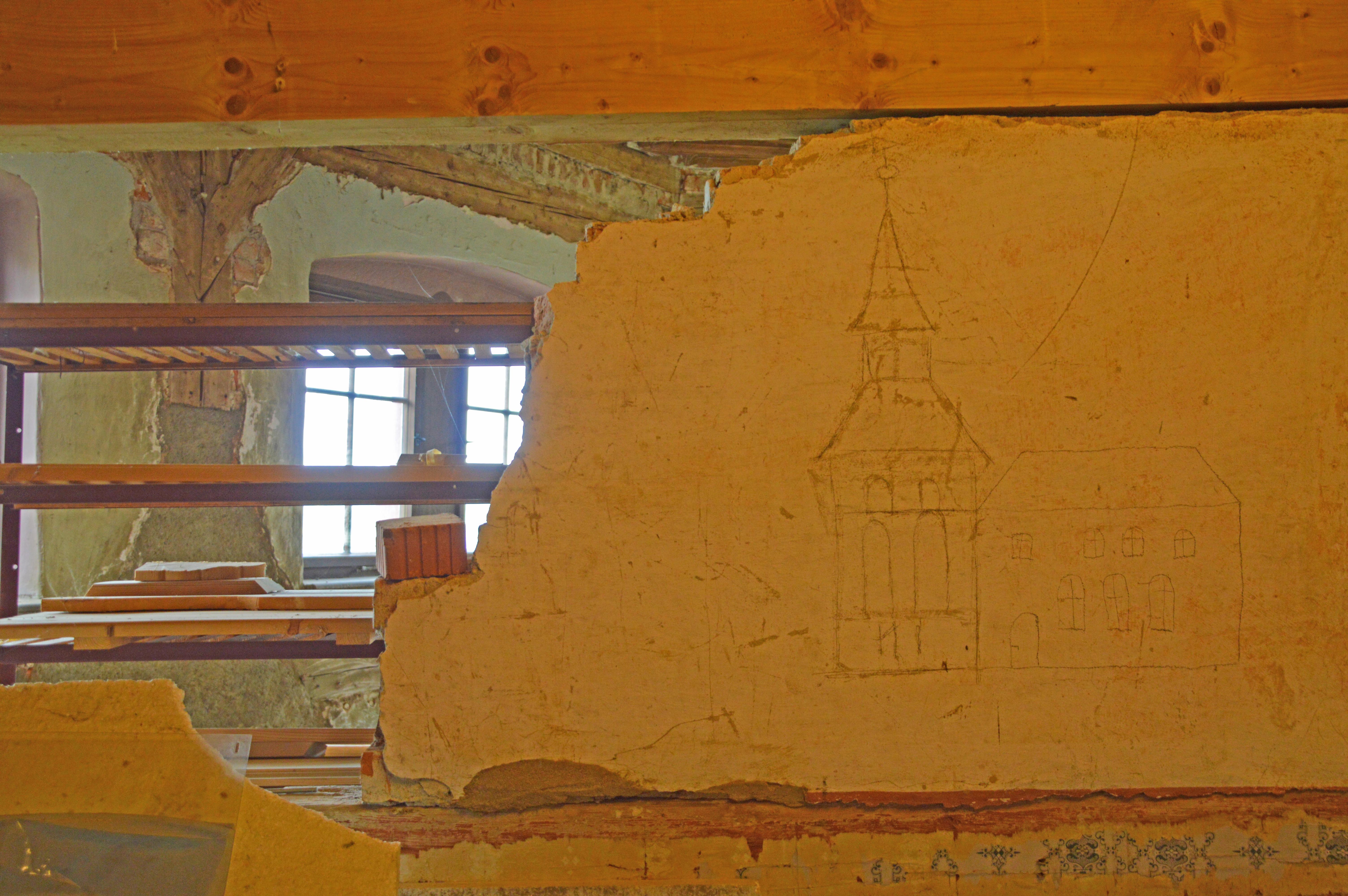 Foto einer halb abgerissenen Innenwand, die den Blick freigibt auf dahinterliegende Räumlichkeiten im Dachboden von Schloss Rochsburg.