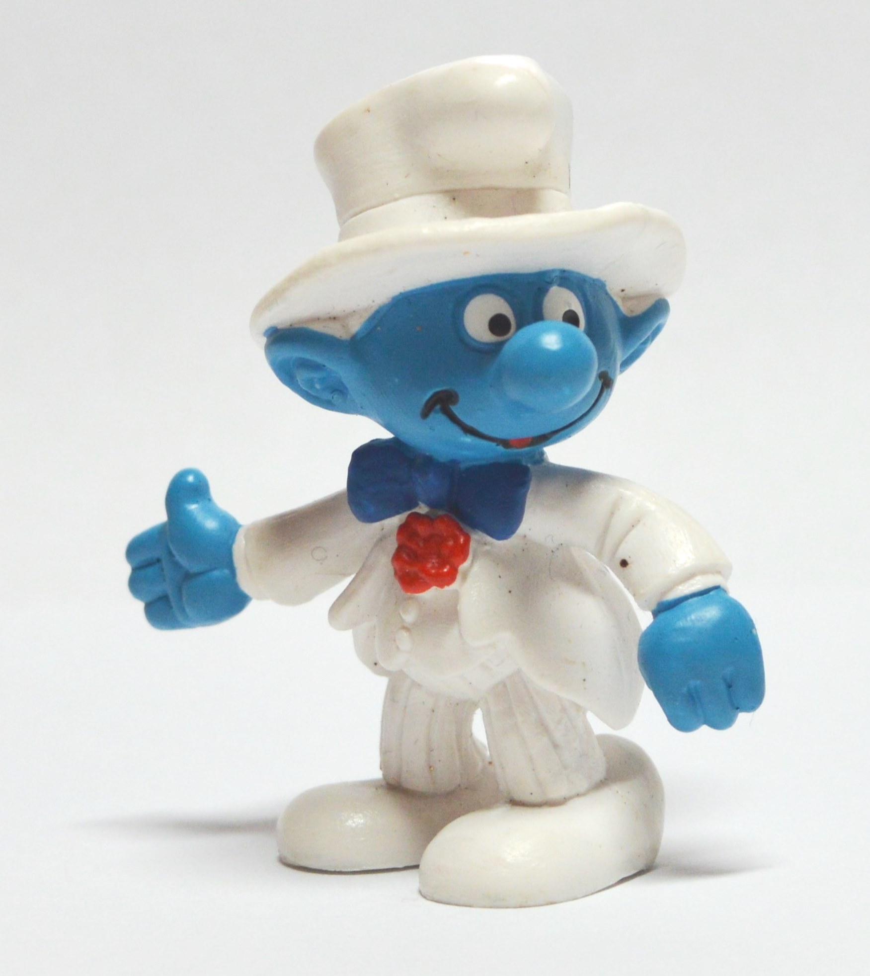 Eine männliche Schlumpf-Figure mit blauem Kopf und blauen Händen trägt einen weißen Anzug und einen weißen Hut.