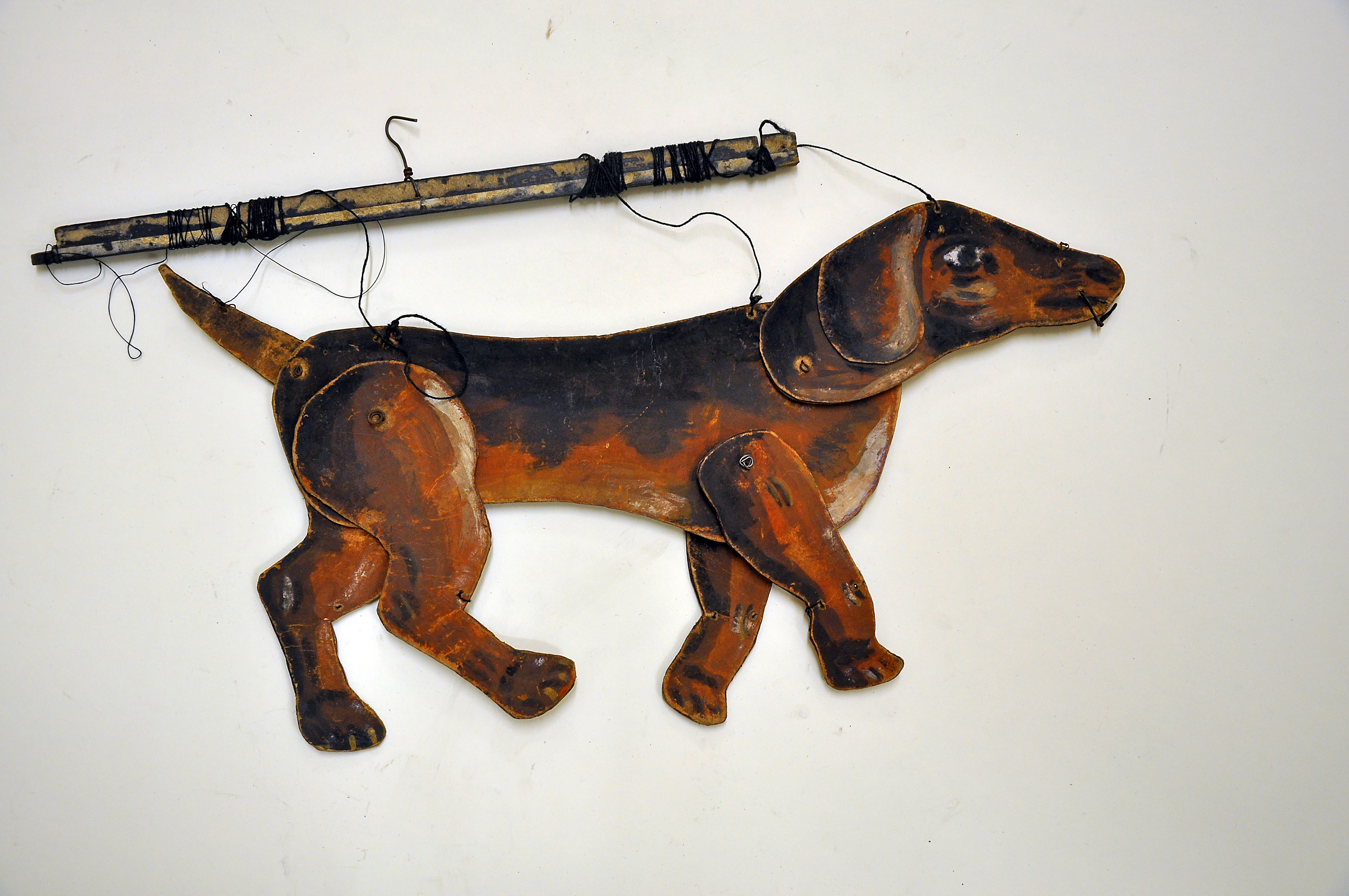 Das Bild zeigt eine Puppentheaterfigur. Es handelt sich um einen Hund, der mit den angebrachten Schnüren vom Puppenspieler bewegt werden kann.