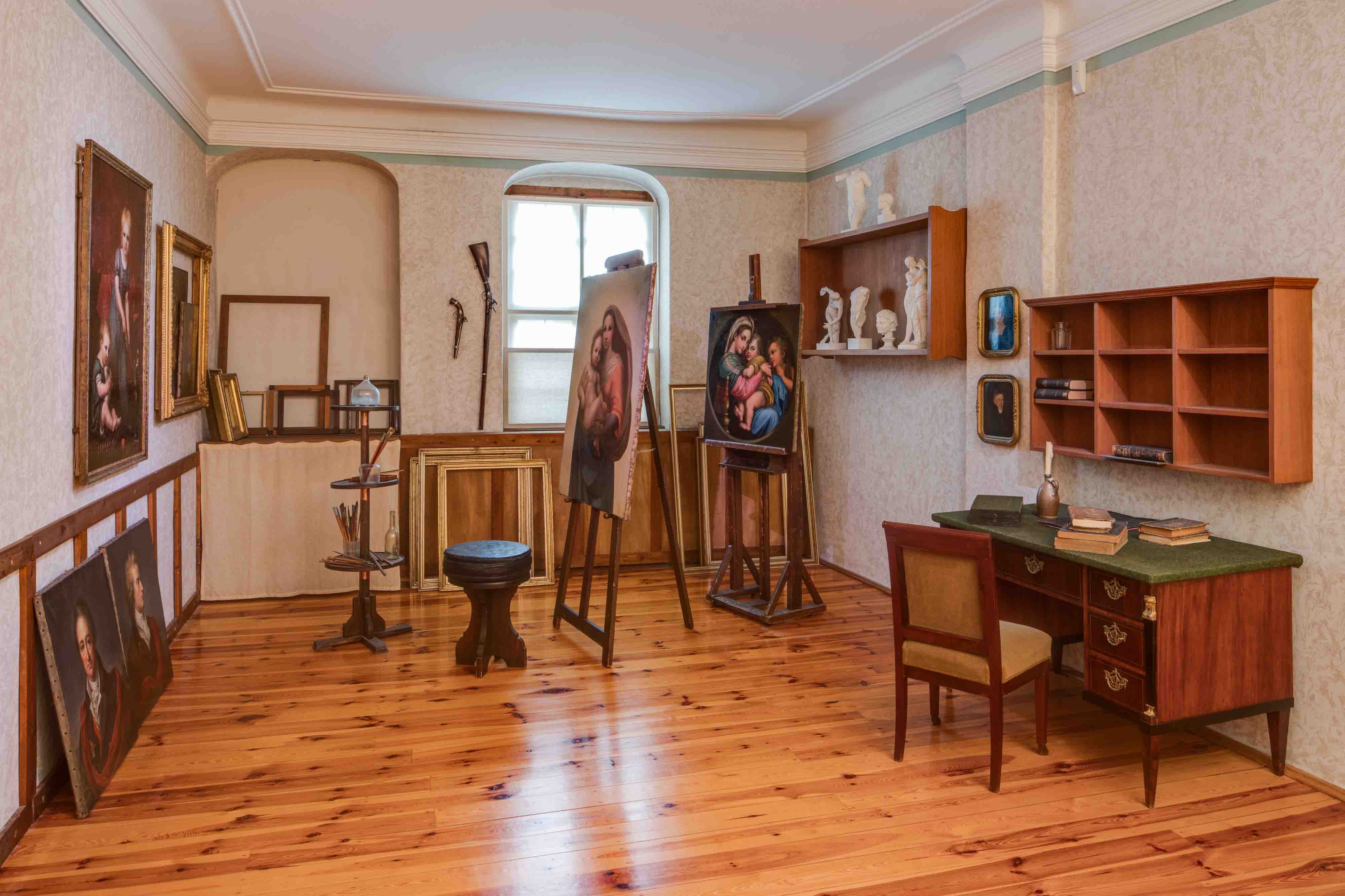 Ein wie ein historisches Künstleratelier anmutender Raum mit Gemälden, Staffeleien, Büchern und Skulpturen